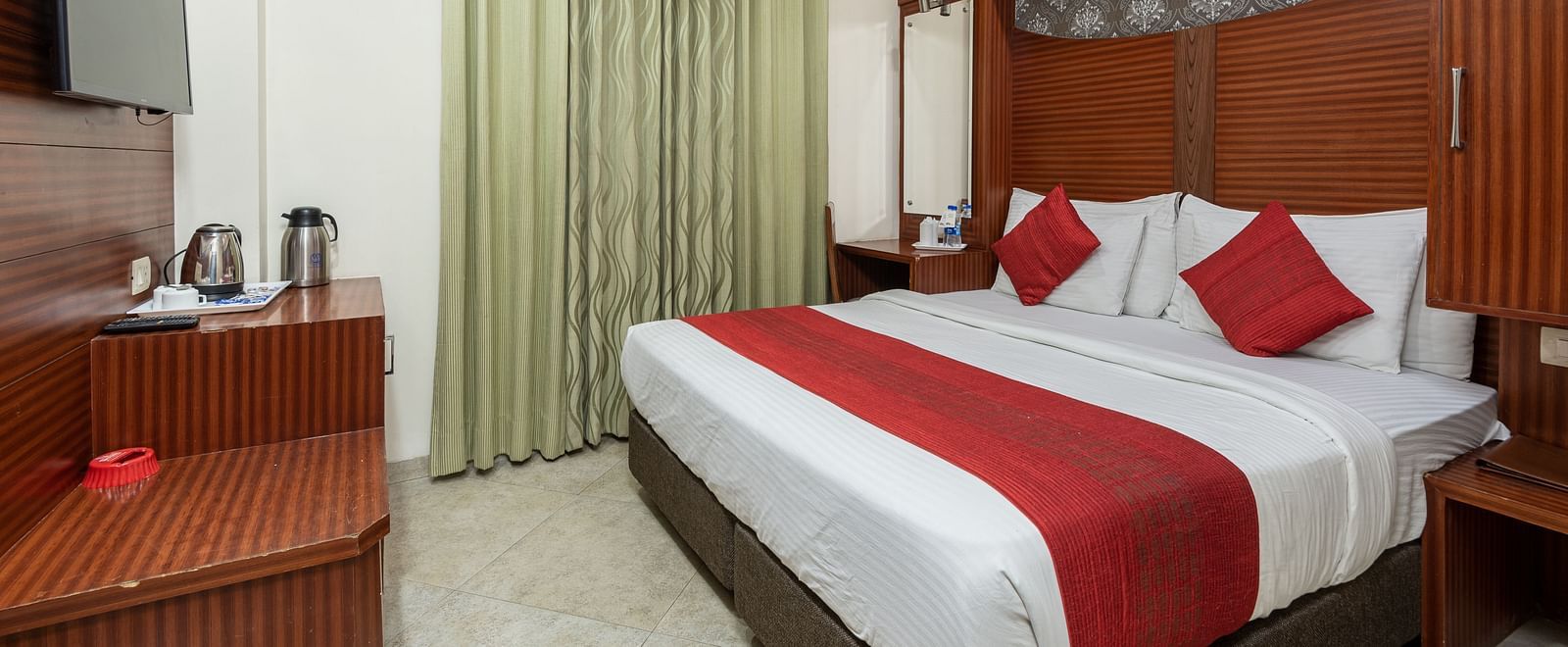 Side view of a deluxe room featuring a king size bed, a TV, and a tea & coffee maker on the table at DLS Hotels The Rock Castle.